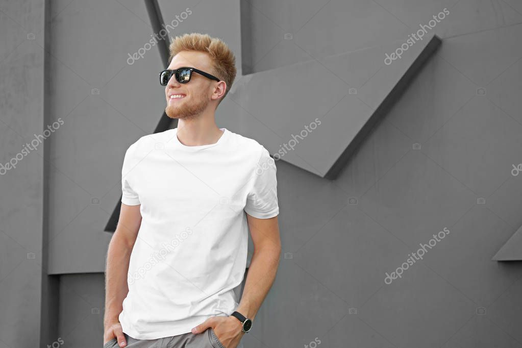 Man in stylish t-shirt near grey wall