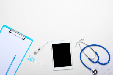 Pano, tablet bilgisayar, stetoskop ve beyaz arka plan üzerinde haplar