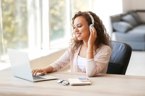 Young African-American student listening to music while preparing for exam — Stock Photo, Image