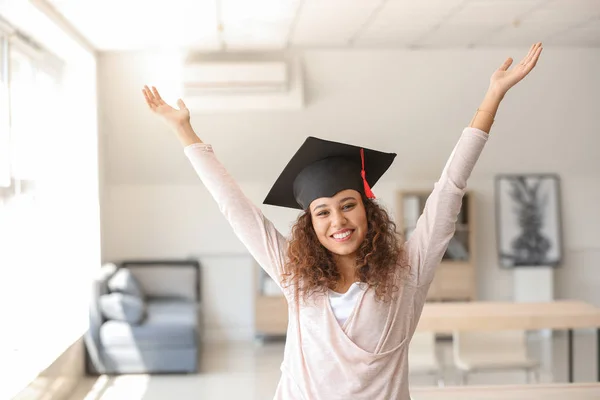 Happy African-American student wearing graduation hat in classroom — Stock Photo, Image