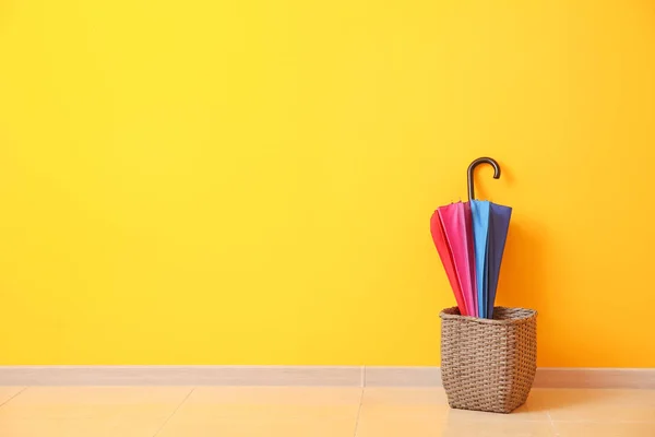 Stylish umbrella with basket near color wall — Stock Photo, Image