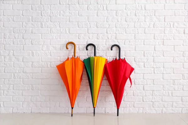 Stylish umbrellas near white brick wall — Stock Photo, Image