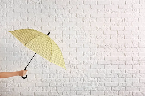 Mão feminina com guarda-chuva elegante no fundo de tijolo branco — Fotografia de Stock