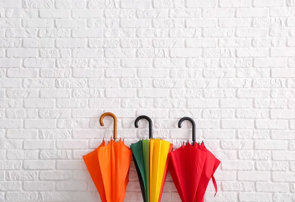 Stylish umbrellas near white brick wall — Stock Photo, Image