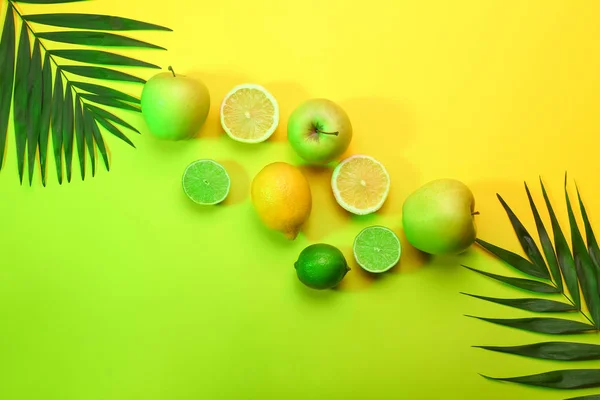 Tasty fruits and tropical leaves on color background — Stock Photo, Image