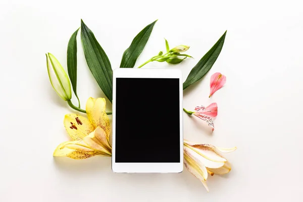 Tablet komputer, kwiaty i liście na białym tle — Zdjęcie stockowe