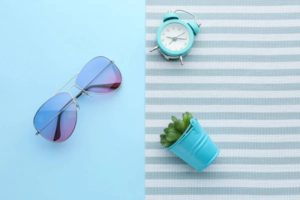 Stylish sunglasses with alarm clock and plant on color background — Stock Photo, Image