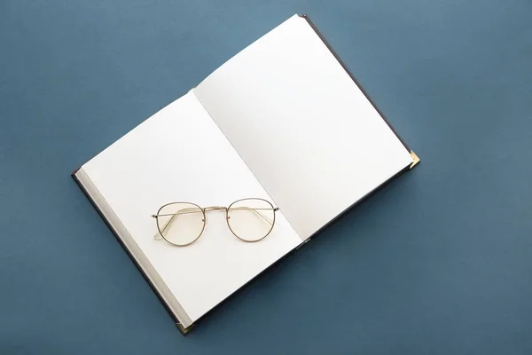 Livro aberto com óculos sobre fundo cinza — Fotografia de Stock