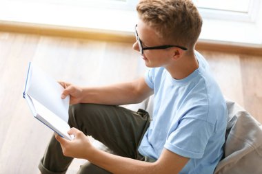 Kapalı mekanda sınava hazırlanırken erkek öğrenci okuma kitabı