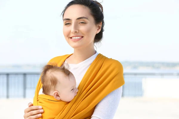 Giovane madre con il suo bambino in fionda camminare all'aperto — Foto Stock