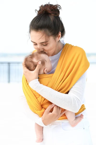 Giovane madre con il suo bambino in fionda camminare all'aperto — Foto Stock