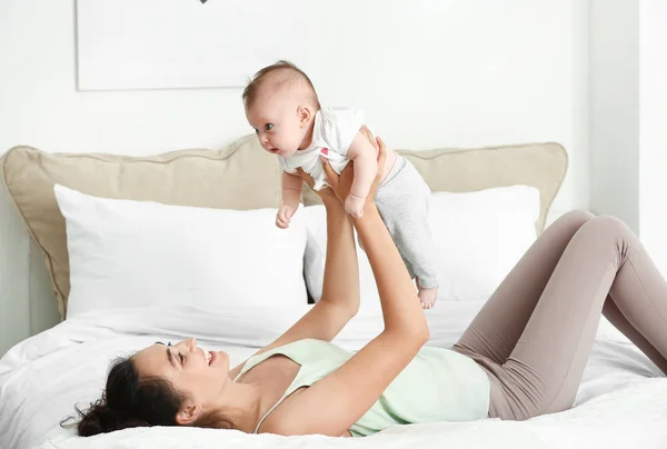 Happy mother with cute little baby lying on bed — Stock Photo, Image