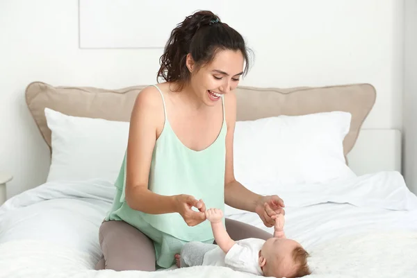 Gelukkige moeder met schattige kleine baby op bed thuis — Stockfoto