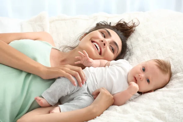 Feliz madre con lindo bebé acostado en la cama —  Fotos de Stock