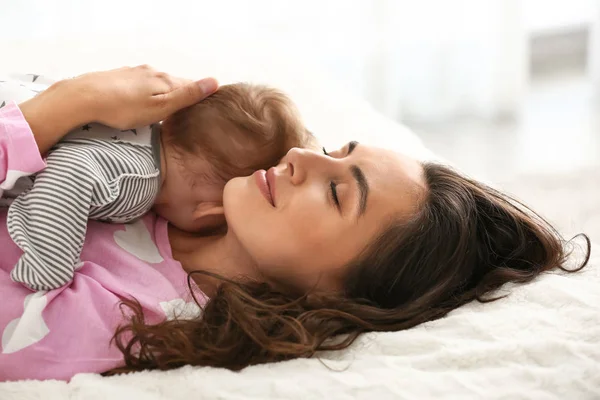 Yatakta yatarken sevimli küçük bebek ile mutlu anne — Stok fotoğraf