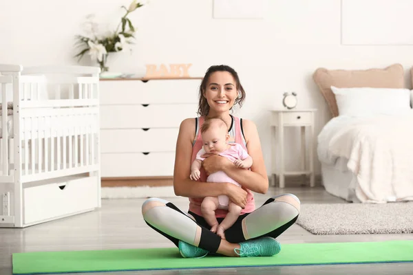 Mãe praticando ioga com bebê pequeno bonito em casa — Fotografia de Stock