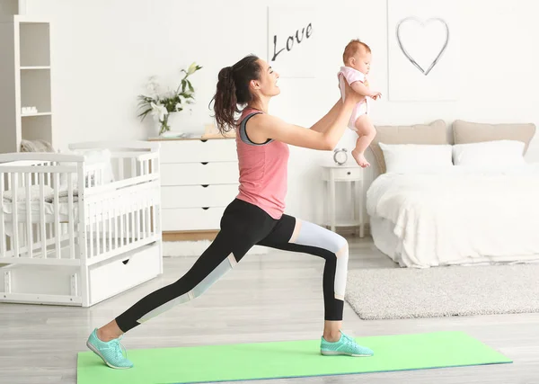 Mãe praticando ioga com bebê pequeno bonito em casa — Fotografia de Stock