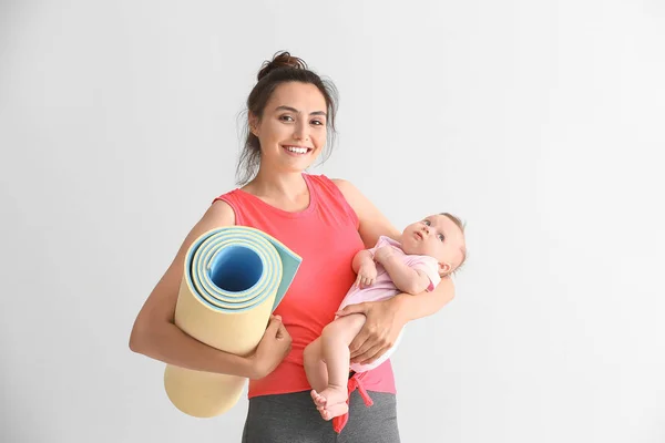 Mother with yoga mat and cute little baby on white background — Stock Photo, Image