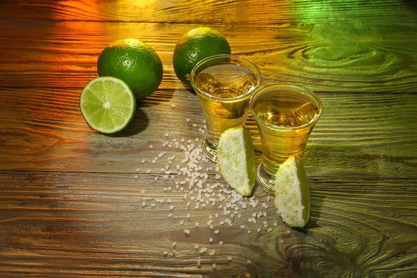Tomas de tequila sabroso con lima y sal en la mesa de madera —  Fotos de Stock