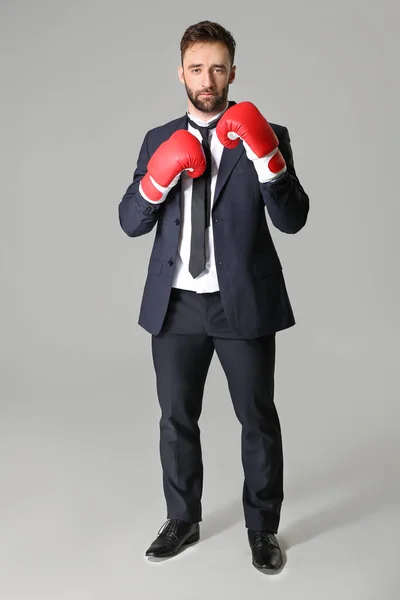 Businessman in boxing gloves on grey background — Stock Photo, Image
