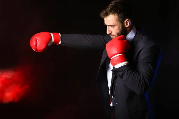 Geschäftsmann in Boxhandschuhen auf dunklem Hintergrund — Stockfoto