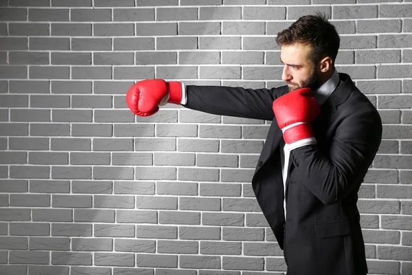 Businessman in boxing gloves against brick wall