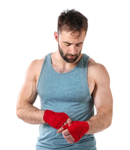 Starker männlicher Boxer, der vor weißem Hintergrund Armbänder anlegt — Stockfoto