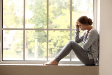 Pencere yakınında panik atak geçiren kadın