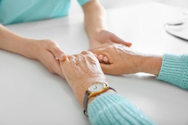 Klinikte yaşlı kadını destekleyen doktor, yakın çekim