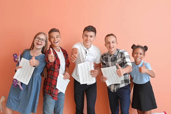 Compañeros felices con los resultados de la prueba de la escuela en el fondo de color — Foto de Stock