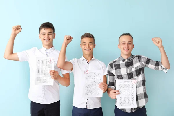 Niños felices con los resultados de la prueba de la escuela en el fondo de color —  Fotos de Stock