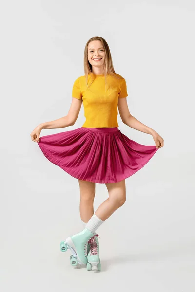 Beautiful young girl on roller skates against light background — Stock Photo, Image