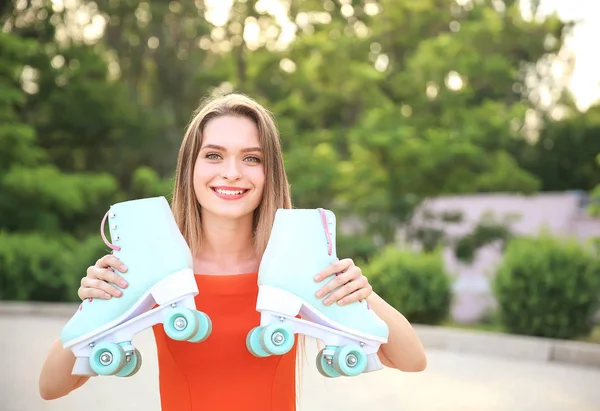 Beautiful young woman with roller skates outdoors — Stock Photo, Image