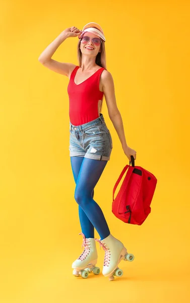 Hermosa mujer joven en patines sobre fondo de color — Foto de Stock