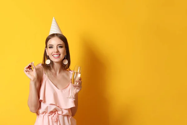 Glückliche Frau mit Glas Champagner und Party-Pfeife auf farbigem Hintergrund — Stockfoto