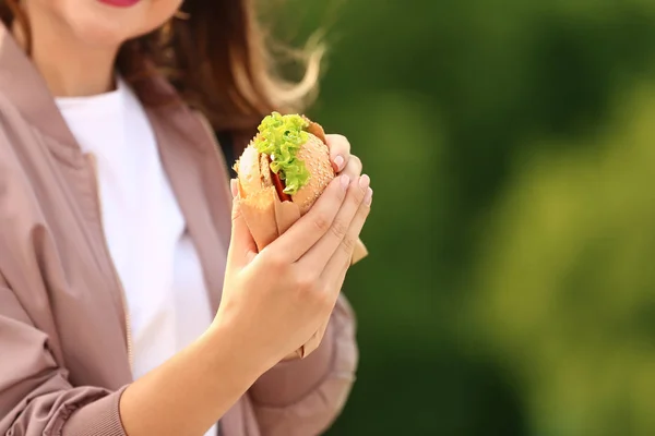 Beautiful young woman with tasty burger outdoors — Stock Photo, Image