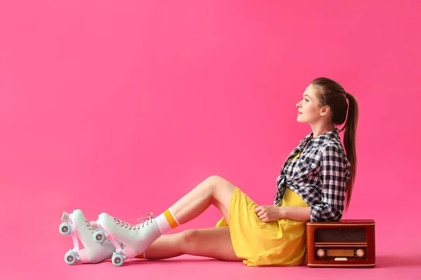 Schöne junge Frau auf Rollschuhen und mit Retro-Radioempfänger vor farbigem Hintergrund — Stockfoto