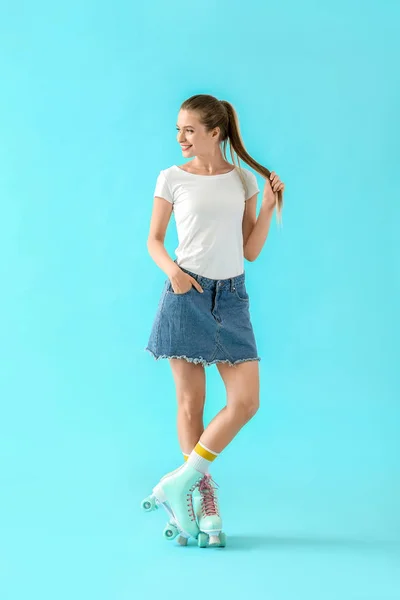 Beautiful young woman on roller skates against color background — Stock Photo, Image