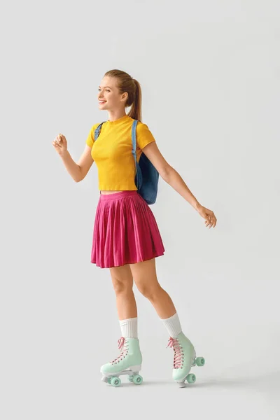 Beautiful young girl on roller skates against light background — Stock Photo, Image