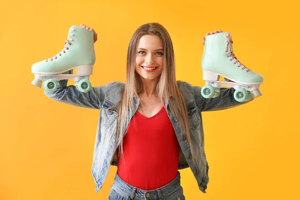 Beautiful young woman with roller skates on color background — Stock Photo, Image