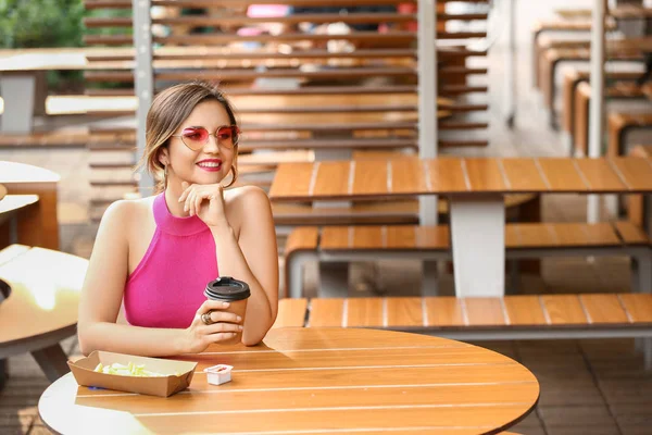 Beautiful young woman drinking tasty coffee in outdoor cafe — Stock Photo, Image