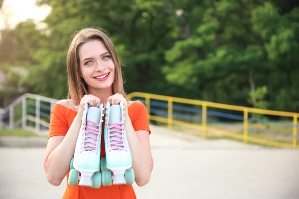 Beautiful young woman with roller skates outdoors — Stock Photo, Image