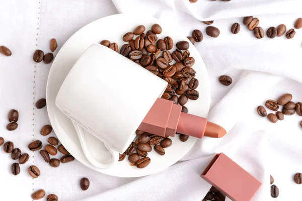 Lippenstift met koffiebonen en kopje op plaat — Stockfoto