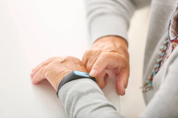 Elderly woman with fitness band checking her pulse, closeup