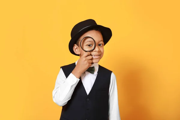 Piccolo detective afro-americano con lente di ingrandimento su sfondo a colori — Foto Stock