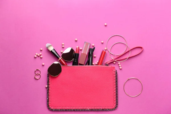 Saco com cosméticos de maquiagem e acessórios femininos em fundo colorido — Fotografia de Stock