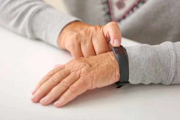Mujer mayor con banda de fitness comprobando su pulso, primer plano — Foto de Stock