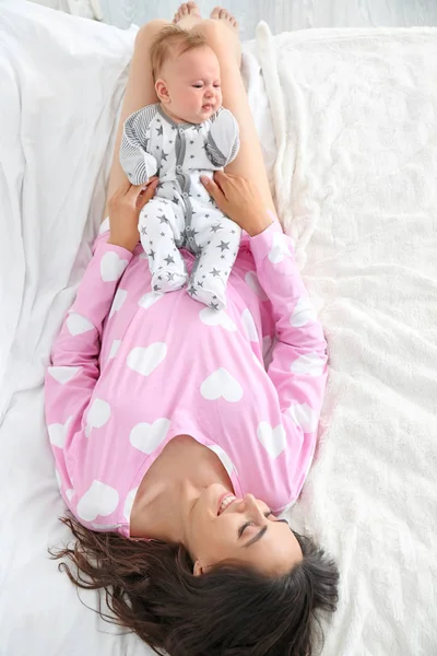 Madre feliz con lindo bebé acostado en la cama, vista superior —  Fotos de Stock