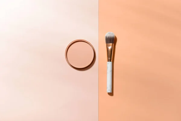 Makeup brush with facial powder on color background