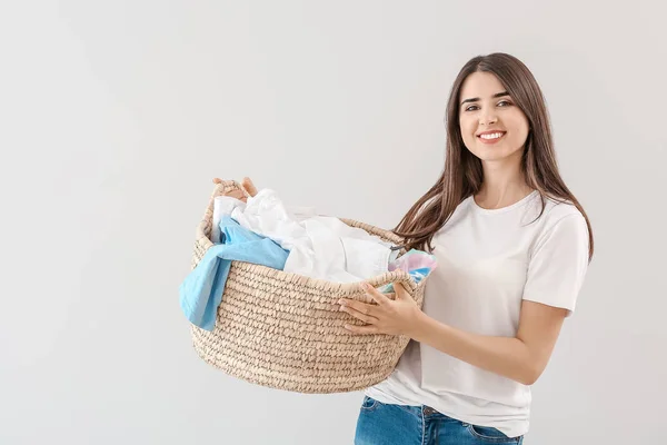 Beautiful young woman with laundry on light background — Stock Photo, Image